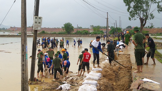 Các đoàn viên thanh viên đang hốt cát, đất gia cố những đoạn đường bị nước lũ phá vỡ