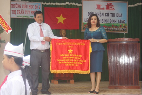 Bà Hoàng Ngọc Tố Nương - Phó Trưởng phòng GDĐT huyện Tuy Phước  trao cờ thi đua của UBND tỉnh cho thầy và trò trường TH số 2 thị trấn Tuy Phước