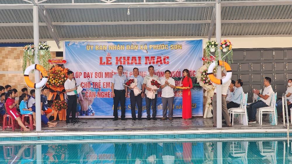 Đồng chí Nguyễn Hùng Tân - Phó Chủ tịch UBND huyện và Lãnh đạo xã Phước sơn tặng hoa cảm ơn Công ty hỗ trợ kinh phí cho lớp dạy bơi